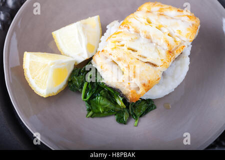 Gebratener Kabeljau Filets, Spinat und Zitrone auf dem Teller Stockfoto