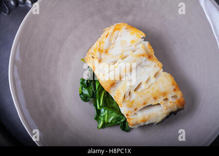 Gebratener Kabeljau Filets und Spinat auf einen Teller. Stockfoto