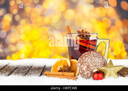 heißer Glühwein auf verschneiten Holzbohlen vor hellen goldenen Bokeh Lichter Hintergrund gewürzt Stockfoto