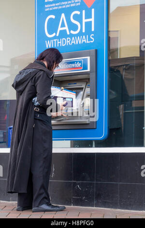 Ein Mann gekleidet in schwarz aus einer Nationwide Building Society ATM oder Geldautomaten Bargeld abheben Stockfoto