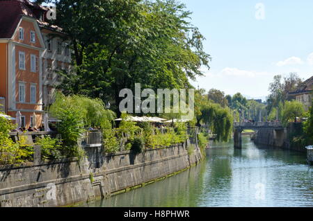 Ljubljana, Slowenien, 25. September 2016: Stadtzentrum, Fluss Ljubljanica. Manche Leute sitzen im Garten Küsten Pub. Stockfoto