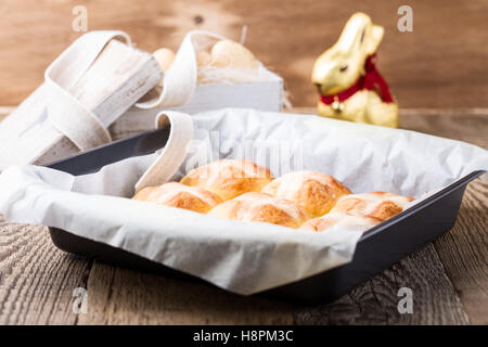 Hausgemachte Ostern Hot Cross Brötchen im Bäckerei-Tray auf Holztisch Stockfoto