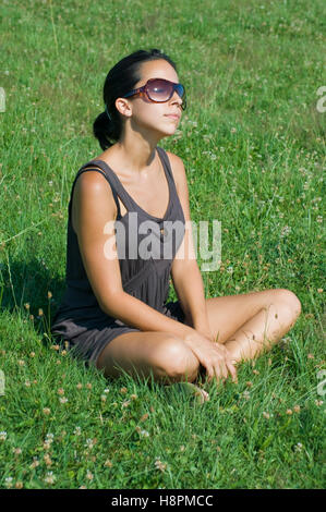 Junge Frau auf der Wiese an einem sonnigen Tag entspannend Stockfoto