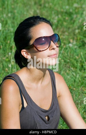 Junge Frau auf der Wiese an einem sonnigen Tag entspannend Stockfoto