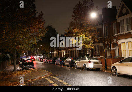 Herbst Blätter bedecken die Bürgersteige und Straßen in einer typischen Süd-London-Straße nach Einbruch der Dunkelheit auf eine nasse Nacht Stockfoto