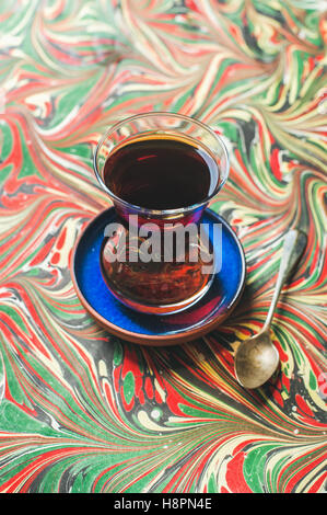 Türkischer Tee in traditionellen Tulpenglas und Löffel, bunten Hintergrund Stockfoto