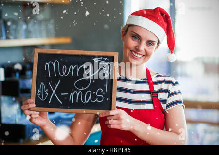 Zusammengesetztes Bild Porträt der Kellnerin mit Schiefer mit merry x-mas-Schild Stockfoto