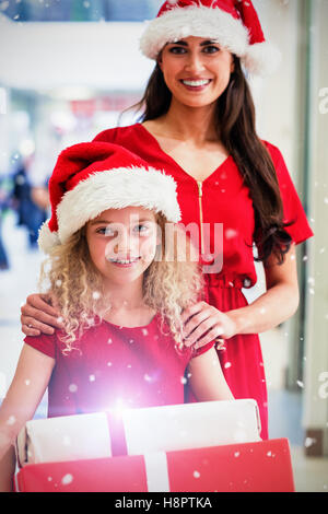 Zusammengesetztes Bild Porträt von Mutter und Tochter in Weihnachten Kleidung stehend mit Geschenken Stockfoto