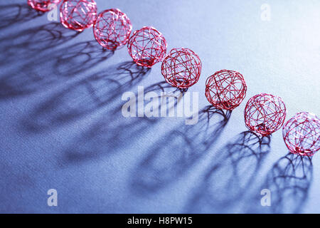 Set mit Kugeln aus roter Draht in einer Reihe mit Schatten Stockfoto