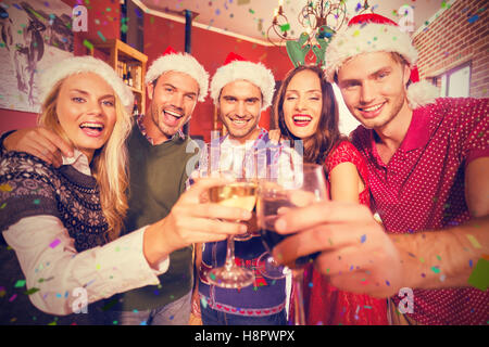 Zusammengesetztes Bild des Porträts von Freunden tragen Weihnachtsmützen Toasten Stockfoto