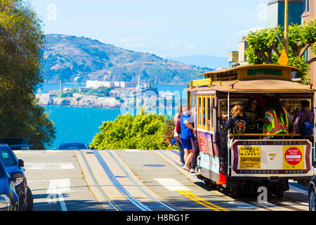 Tele komprimierten Blick auf Alcatraz Island und Seilbahn touristischen Passagieren am Kamm der Hyde Street am sonnigen Tag voller Stockfoto