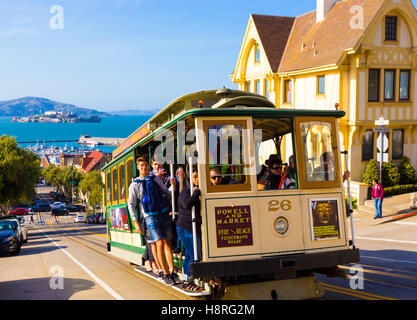 Nahaufnahme des nahenden Hyde Street Seilbahn voller Menschen stehen auf der äußeren Plattform steilen Fahrt mit Alcatraz genießen Stockfoto