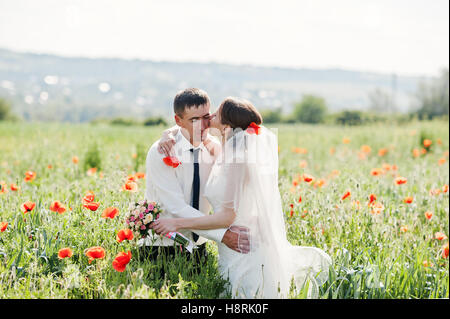 Hochzeitspaar auf dem Feld von Mohn in der Liebe Stockfoto