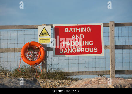 Gefahr melden Sie an einem Strand mit Sicherheitsgurt Linie und Rettungsring. Baden und paddeln gefährlich in weißer Schrift auf rot. Stockfoto