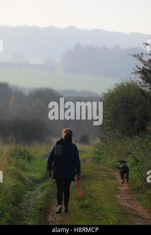 Eine Frau, die ihren Hund auf den Shabd Weg-Wanderweg in der Nähe von Ringstead in North Norfolk. Stockfoto