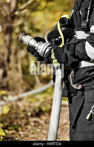 Feuerwehrmann mit Hochdruck-Wasserschlauch Löschen eines Brandes Stockfoto