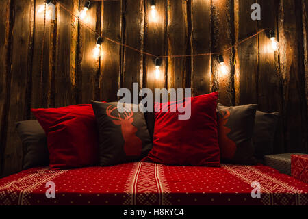 Weihnachten dekoriert Platz in einem Raum mit alten Holzwand, Lampen, Rotwild Kissen und plaid Stockfoto
