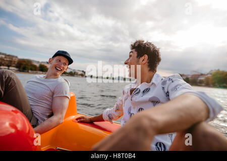 Im Freien Schuss von zwei jungen Freunden sitzen im Tretboot. Jungs im Teenageralter Bootfahren im See zu genießen. Stockfoto