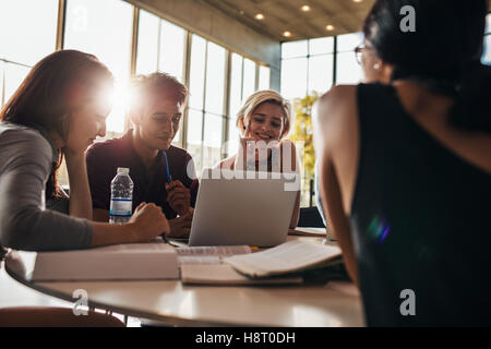 Mann und Frau, die im Unterricht zusammen sitzen. universitätsstudenten, die in der Bibliothek an einem Laptop arbeiten. Stockfoto