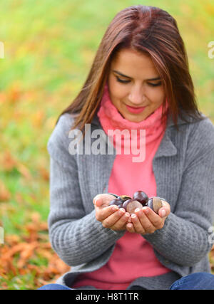 Mädchen in ihren Händen hält viele Kastanien Stockfoto