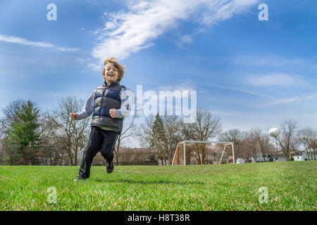 Kleiner Junge läuft auf einem Fußballfeld Stockfoto