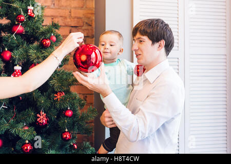 Sohn und Vater schmücken den Weihnachtsbaum zu Hause im Wohnzimmer Stockfoto