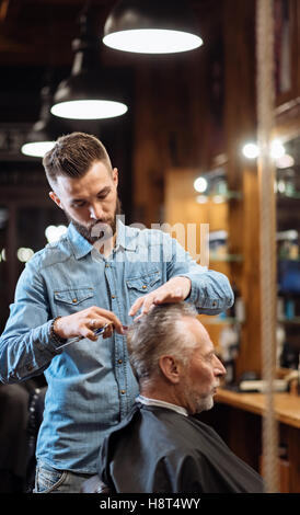 Alter Mann mit Haarschnitt von jungen Spezialisten Stockfoto