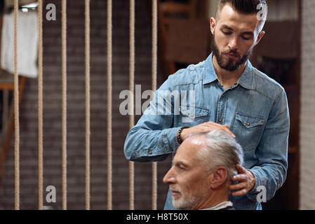 Gut aussehend Friseur Kopfmassage, senior Client zu tun Stockfoto