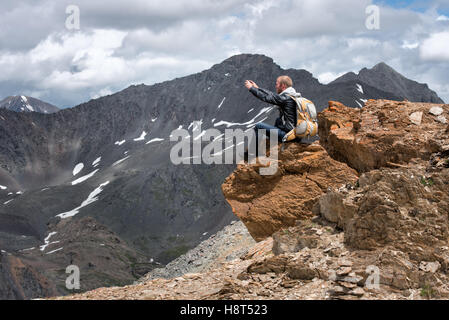 Tourist mit einem Rucksack sitting on Top of Mountain und fotografieren das Telefon. Die Höhe von 3000 Meter. Stockfoto