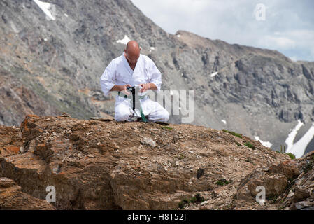 Der Mann in einem Kimono sitzt im Lotussitz auf Berg- und gerade die Bilder in der Kamera. Stockfoto