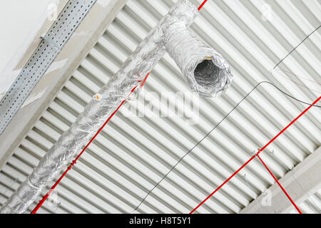 Lüftungsrohre in Silber Isolierung Material und Feuer Sprinkler auf rote Rohr hängen von der Decke in neue Gebäude. Stockfoto