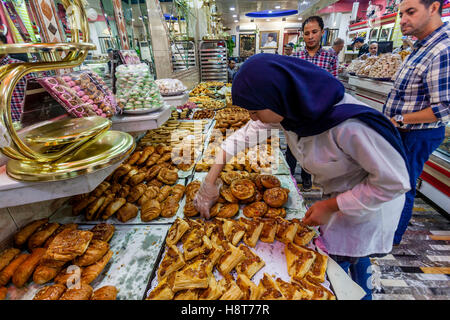 Eine Arbeitnehmerin wählt Gebäck aus der Anzeige in der Dallas-Patisserie, Tetouan, Marokko Stockfoto