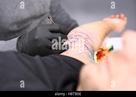Tatoo auf der Schulter. Tattoo, Tattoo-Künstler tut das Tattoo auf die Hand des Mannes. Stockfoto