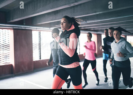 Attraktive junge urban runner Stimulation ihrer Teamkollegen, als sie sprintet durch eine Tiefgarage in einem Gesundheit und Fitness anhand von quantitativen Simulatio Stockfoto