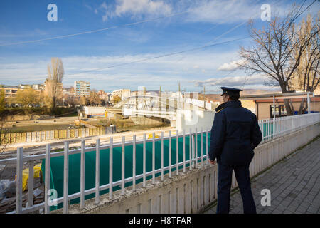 Kosovo-Polizist Ibar-Brücke in Mitrovica, Symbol für die Teilung zwischen den albanischen und serbischen Teilen der Stadt zu beobachten Stockfoto