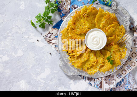 Traditionelle hausgemachte Kartoffelpuffer, serviert mit saurer Sahne-Sauce, Ansicht von oben. Chanukka-Festessen auf Vintage konkrete staatlich Stockfoto