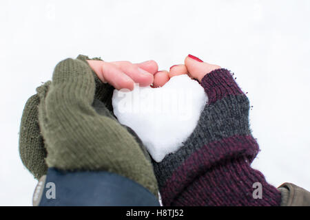 Paare-Hände halten einen herzförmigen Schneeball Stockfoto