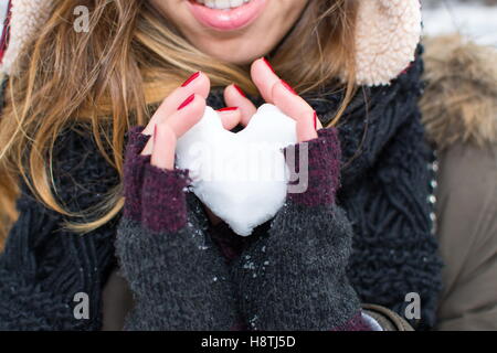 Frau Hände halten Herz geformten Schneeball im freien Stockfoto