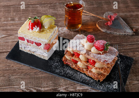 Sahnetorte Erdbeer Glasur Mille Feuille Dessert süß auf schwarzem Stein Stockfoto