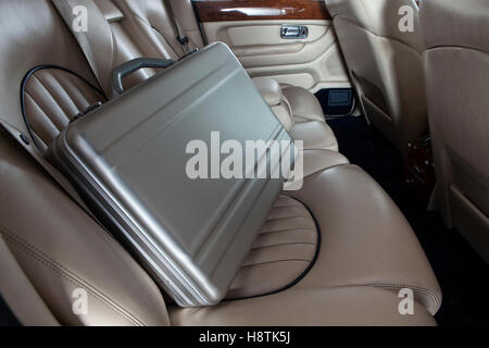 Luxus Metall Aktenkoffer auf dem Auto-Rücksitz. Creme Leder Stockfoto