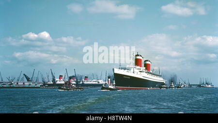 AJAXNETPHOTO. 1950ER JAHRE (CA.). SOUTHAMPTON, ENGLAND. -UNITED STATES LINES S.S. VEREINIGTE STAATEN NACH INNEN GEBUNDEN MIT FÜNF SCHLEPPER ANWESEND; CUNARD LINER RMS QUEEN MARY CAN GESEHEN AUF DER LINKEN SEITE ANGEDOCKT WERDEN.   FOTOGRAF: UNBEKANNT © DIGITAL COPYRIGHT AJAX VINTAGE BILD BIBLIOTHEK BILDQUELLE: AJAX VINTAGE BILDBIBLIOTHEK SAMMLUNG REF: 160606 1 Stockfoto