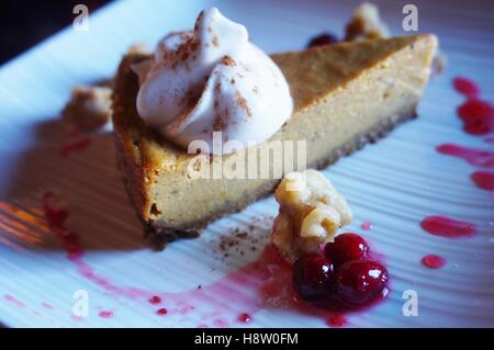 Eine vegane Kürbis-Kuchen Käsekuchen mit Kokos Schlagsahne Sahne und frische Preiselbeeren Stockfoto