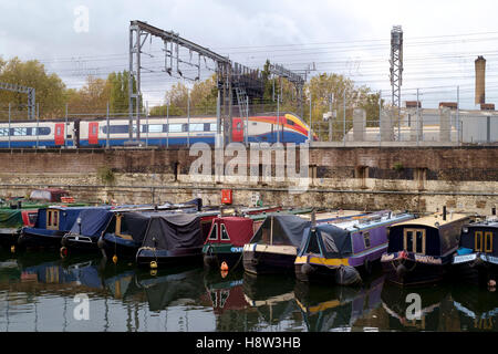 Die Regents Canal in St Pancras in London.  Eine Lokomotive von East Midlands Trains neben einer Kanal-Becken von festgemachten Narrowboats. Stockfoto