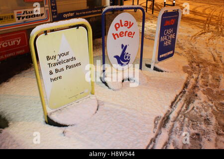 Geldautomat hier Lotto und Reisen Karte-Zeichen vor einem Geschäft mit Schnee bedeckt Stockfoto