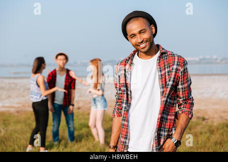 Lächelnd afroamerikanischen jungen Mann während seiner Freunde reden im Freien stehen Stockfoto