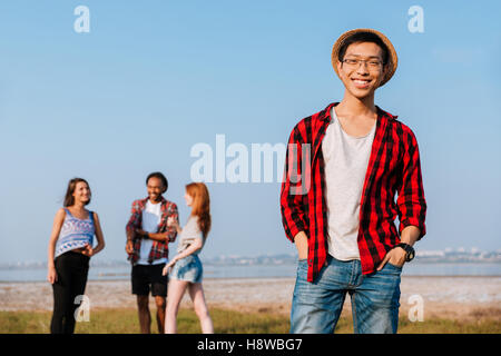 Fröhlich asiatischen jungen Mann während seiner Freunde im freien sprechen Stockfoto