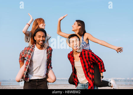 Zwei glückliche junge Paare geben hohe fünf und Spaß im freien Stockfoto