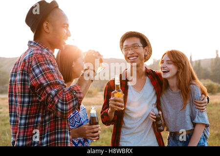 Zwei glückliche junge Paare reden und trinken Bier und Limo zusammen Stockfoto