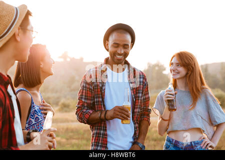 Gruppe von lächelnden jungen Freunden stehen und reden im freien Stockfoto