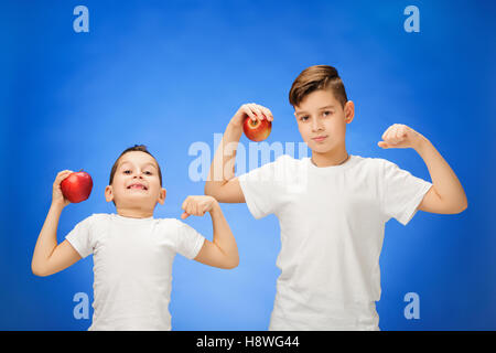 Hübsche kleine Jungs mit zwei roten Äpfeln. Studio-Porträt über blauem Hintergrund Stockfoto